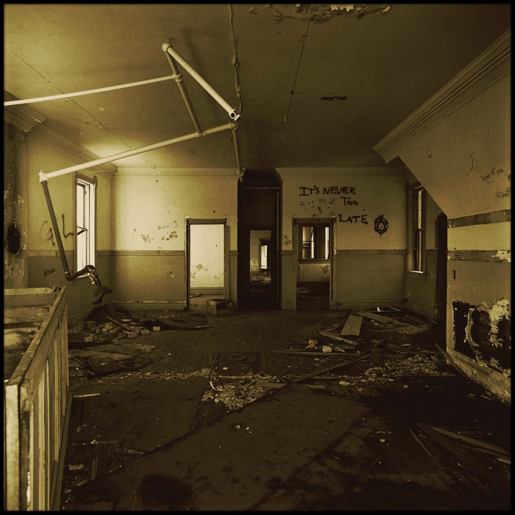 abandoned room with the words 'it's never too late' written on the wall